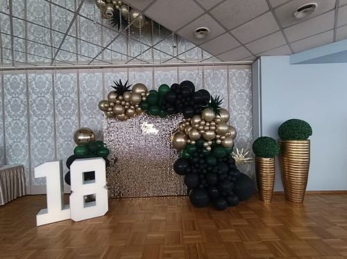 Ścianka balonowa kwadrat na stelażu 2x2 m z cekinami złoto szampańskie, girlanda butelkowa zieleń-czarno-złota, cyfry LED 18. Montaż dekoracji Tychy.