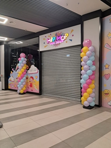 Słupy balonowe reklamowe przed wejściem do sklepu, dekoracja otwarcia w kolorach firmowych, Zabawne Wydry realizacja B2B.